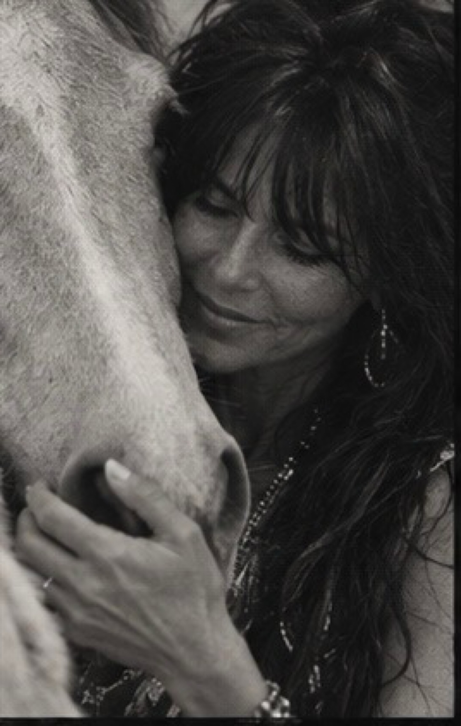 Maureen Steele resting her face against a horse, in black and white.